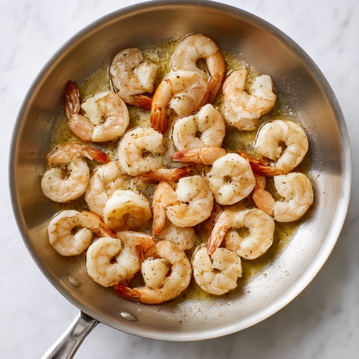 Shrimp cooking in a skillet with a garlic butter sauce, ready to be glazed in honey garlic sauce for a delicious finish.